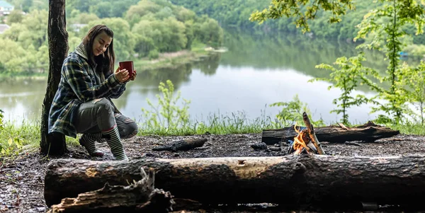 Young Woman Forest River Warms Fire Drinks Hot Drink — Stock Photo, Image
