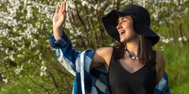 İlkbaharda çiçek açan ağaçların arasında şapkalı çekici bir kız..