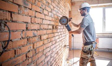 İş kıyafetleri içinde profesyonel bir müteahhit kesme aracı ile çalışır..