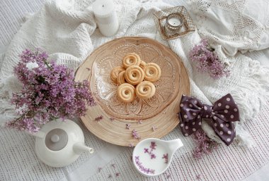 Yatakta bahar çiçekleri, süt ve kurabiye ile ev kompozisyonu.