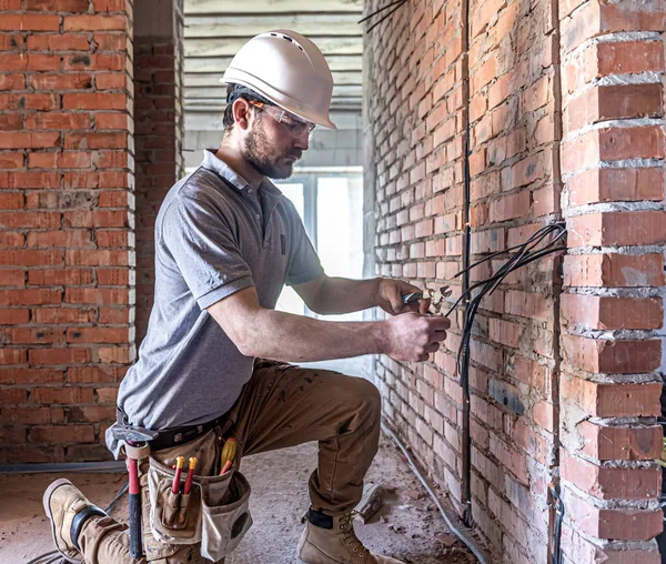 A construction electrician cuts a voltage cable during a repair.