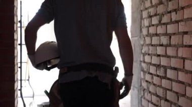 İnşaat alanında elinde miğferi olan bir inşaatçı..