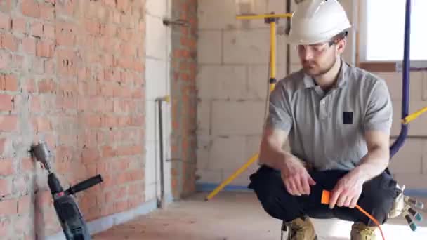 一个戴头盔的建筑工人把钻具塞入出口 — 图库视频影像
