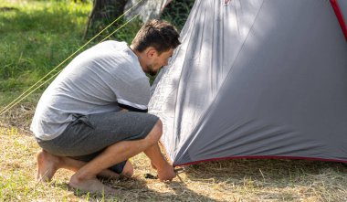 Kamp, seyahat, turizm, yürüyüş konsepti. Dışarıda çadır kuran genç adam..