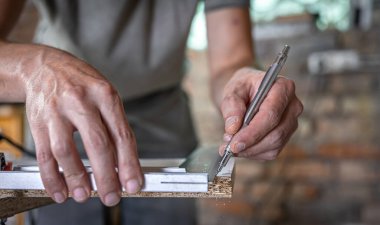 Marangoz ahşabı bir açı aracıyla ölçer ve notlar alır..