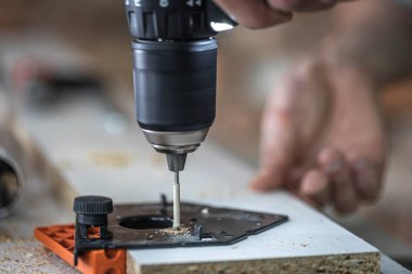 Kendini beceren bir vidayı ahşap şeritteki metal bir deliğe vidalamak bir marangozun işi olan tornavida kullanarak..