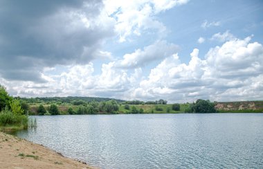 Nehir, orman ve bulutlarla dolu yaz manzarası.