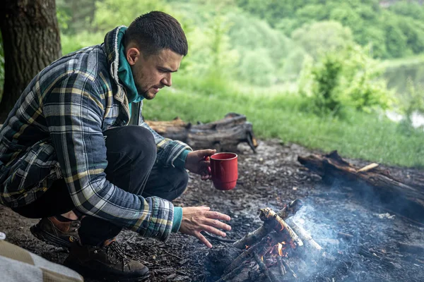 Ein Mann Mit Einem Becher Wärmenden Getränks Wärmt Sich Feuer — Stockfoto