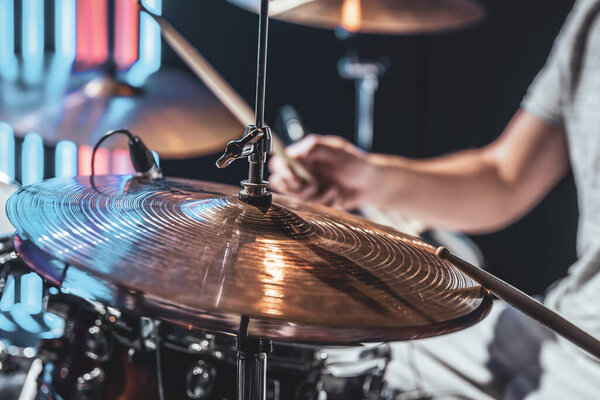Close-up of a drummer playing a drum cymbal, part of a drum kit in a cropped shot.