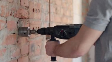 İnşaatçı bir duvar kazıyor, duvarları delecek, inşaat konsepti, elektrik döşeyecek..