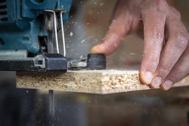 Yapboz ile odun kesme işlemi sırasında bir marangozun ellerine yakın çekim.