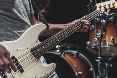 Çalma sürecinde bir müzisyenin elinde bir bas gitarın yakın plan görüntüsü.