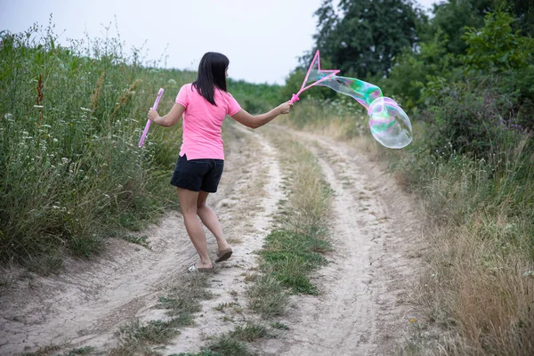 Een Jonge Vrouw Lanceert Enorme Zeepbellen Achtergrond Prachtige Natuur Achteraanzicht — Stockfoto
