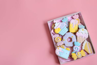 Pembe arka plan fotokopi alanındaki farklı şekillerde renkli zencefilli kurabiyeler..