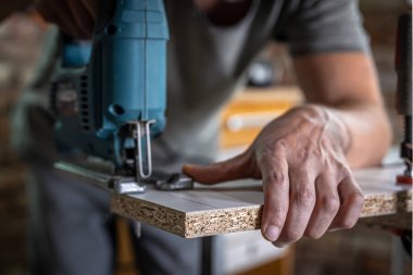 Erkek bir marangoz elektrikli bir yapbozla ağaç keser..