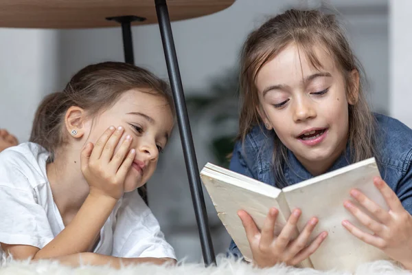 Дві Маленькі Сестри Весело Читають Книгу Разом Лежачи Підлозі Своїй — стокове фото