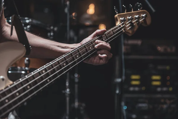 Close-up of a bass guitar in the hands of a musician in the process of playing.