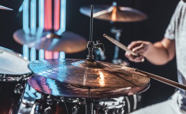 Bateristin davul çalarak yakın plan çekimi. Kesilmiş bir çekimde davul seti parçası..