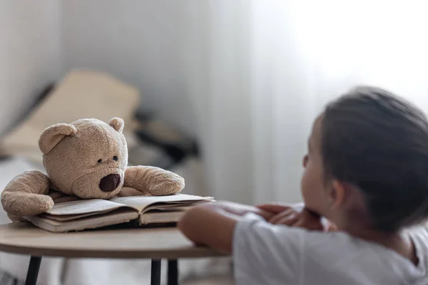 Ein Kleines Mädchen Spielt Mit Ihrem Teddybär Und Einem Buch — Stockfoto