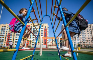 İki küçük kız, ilkokul öğrencisi, okuldan sonra parkta oynuyorlar..