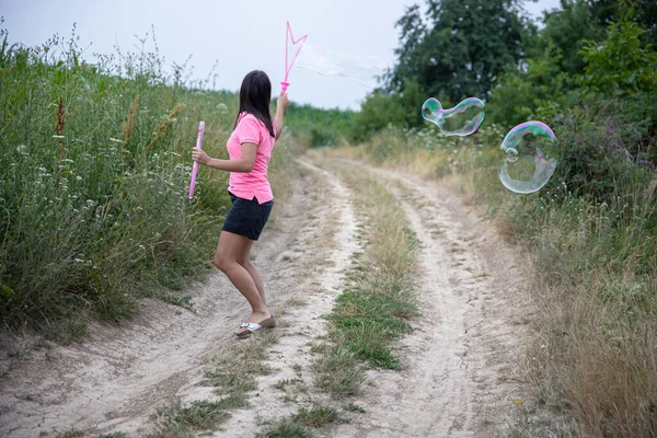 Een Jonge Vrouw Lanceert Enorme Zeepbellen Achtergrond Prachtige Natuur Achteraanzicht — Stockfoto