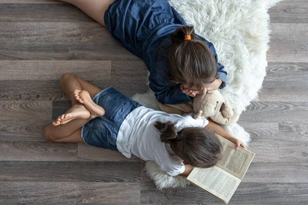 Маленькие Сестры Читают Книгу Плюшевым Мишкой Лежащим Полу Комнате Сверху — стоковое фото