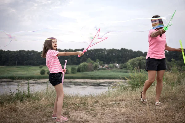 Молодая Женщина Дочь Запускает Огромные Мыльные Пузыри Заднем Плане Красивой — стоковое фото