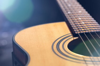 Bokeh ile bulanık bir arkaplanda klasik akustik gitarın yakın plan görüntüsü.