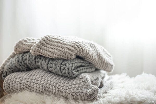 Close-up of a stack of knitted sweaters on a blurred background.