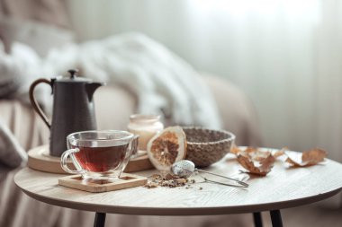 Sonbahar kompozisyonu, bir fincan çay, bir çaydanlık ve arka planda bulanık bir sonbahar dekorasyonu..