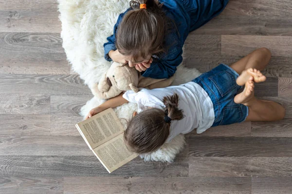 Маленькие Сестры Читают Книгу Плюшевым Мишкой Лежащим Полу Комнате Сверху — стоковое фото