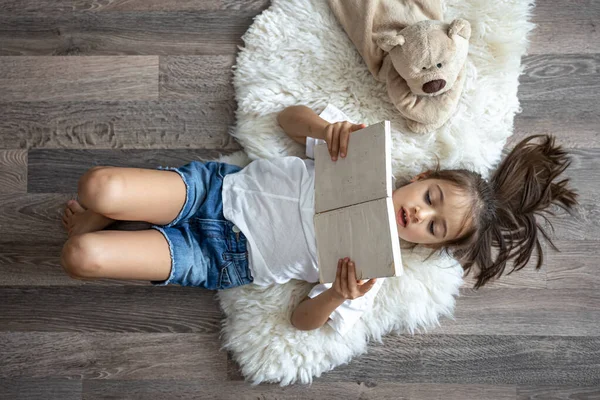 Ребенок Читает Книгу Лежащую Уютном Ковре Дома Своим Любимым Игрушечным — стоковое фото