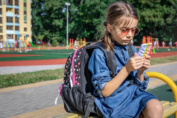 Estudiante Primaria Con Una Mochila Utiliza Teléfono Inteligente Sentado Cerca — Foto de Stock