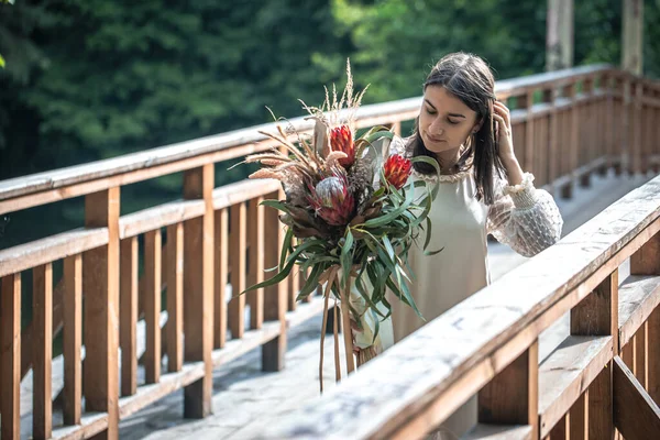 Attraktiv Ung Kvinna Träbro Står Med Bukett Exotiska Blommor — Stockfoto