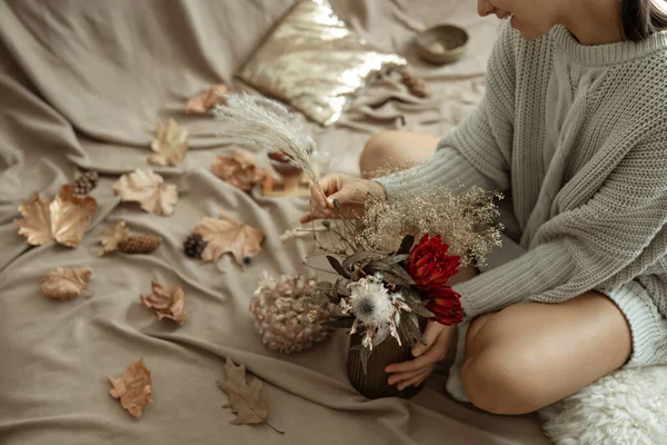 秋の紅葉を背景に 女性の手に秋の花を持つガラス花瓶 — ストック写真