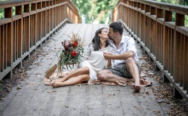 Bir kız ve genç bir adam köprüde oturuyor ve öpüşüyorlar, doğada bir randevu, aşk hikayesi..