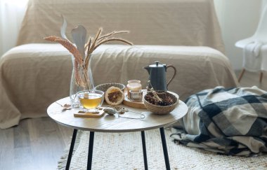 Bir fincan çay, balkabağı, mum ve bulanık bir arka plandaki masanın üzerindeki sonbahar dekorunun ayrıntılarıyla rahat bir ev..