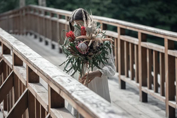 Atrakcyjna Młoda Kobieta Drewnianym Moście Stoi Bukietem Egzotycznych Kwiatów — Zdjęcie stockowe
