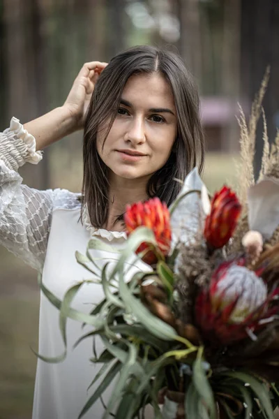 Ung Brunett Kvinna Vit Klänning Med Bukett Blommor Skogen Suddig — Stockfoto