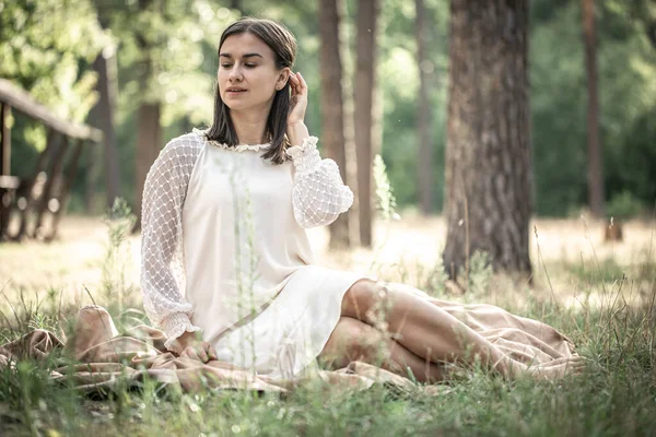 Vacker Ung Brunett Kvinna Vit Klänning Sitter Gräset Skogen Suddig — Stockfoto