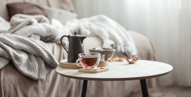 Sonbahar kompozisyonu, bir fincan çay, bir çaydanlık ve arka planda bulanık bir sonbahar dekorasyonu..
