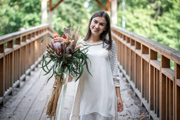 Vacker Flicka Vit Klänning Med Bukett Exotiska Blommor Träbro — Stockfoto