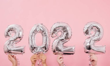 Mutlu yıllar 2022 kutlamaları. Gümüş folyo balonları. Pembe arka planda 2022 numara..