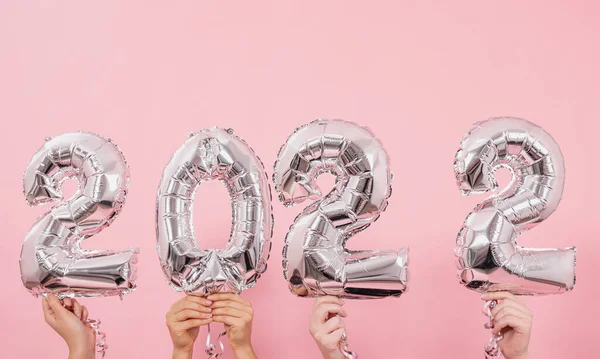 Mutlu yıllar 2022 kutlamaları. Gümüş folyo balonları. Pembe arka planda 2022 numara..