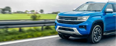 Modern mavi pikap ıslak otoyol boyunca sürüyor, gücü, özgürlüğü ve modern ulaşım enerjisini temsil ediyor..