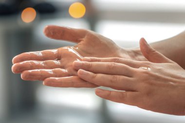 Açık avucundaki parlak yağı nazik bir dokunuşla kapat. Sakin atmosfer, gün ışığı ve modern sağlık ritüeli..