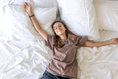 Gençler kollarını kaldırır ve beyaz çarşaflarla gülümserler. Sakin ruh hali, minnettarlık, özen ve yumuşak sabah rahatlığı..