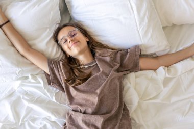 Gençler kollarını kaldırır ve beyaz çarşaflarla gülümserler. Sakin ruh hali, minnettarlık, özen ve yumuşak sabah rahatlığı..