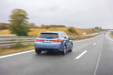 Yağmurdan sonra ıslak bir yolda giden mavi bir kamyonet hareket halindeki güç, dayanıklılık ve güveni temsil ediyor..
