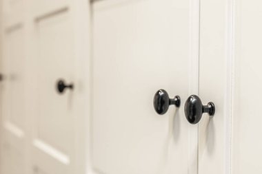 Arka planda yumuşak bokeh ve yuvarlak siyah düğmeleri olan mat önleri kapatın. Modern iç mekanlarda temiz tasarım ve yumuşak minimalizm eğilimleri için kısıtlı bir görünüm.